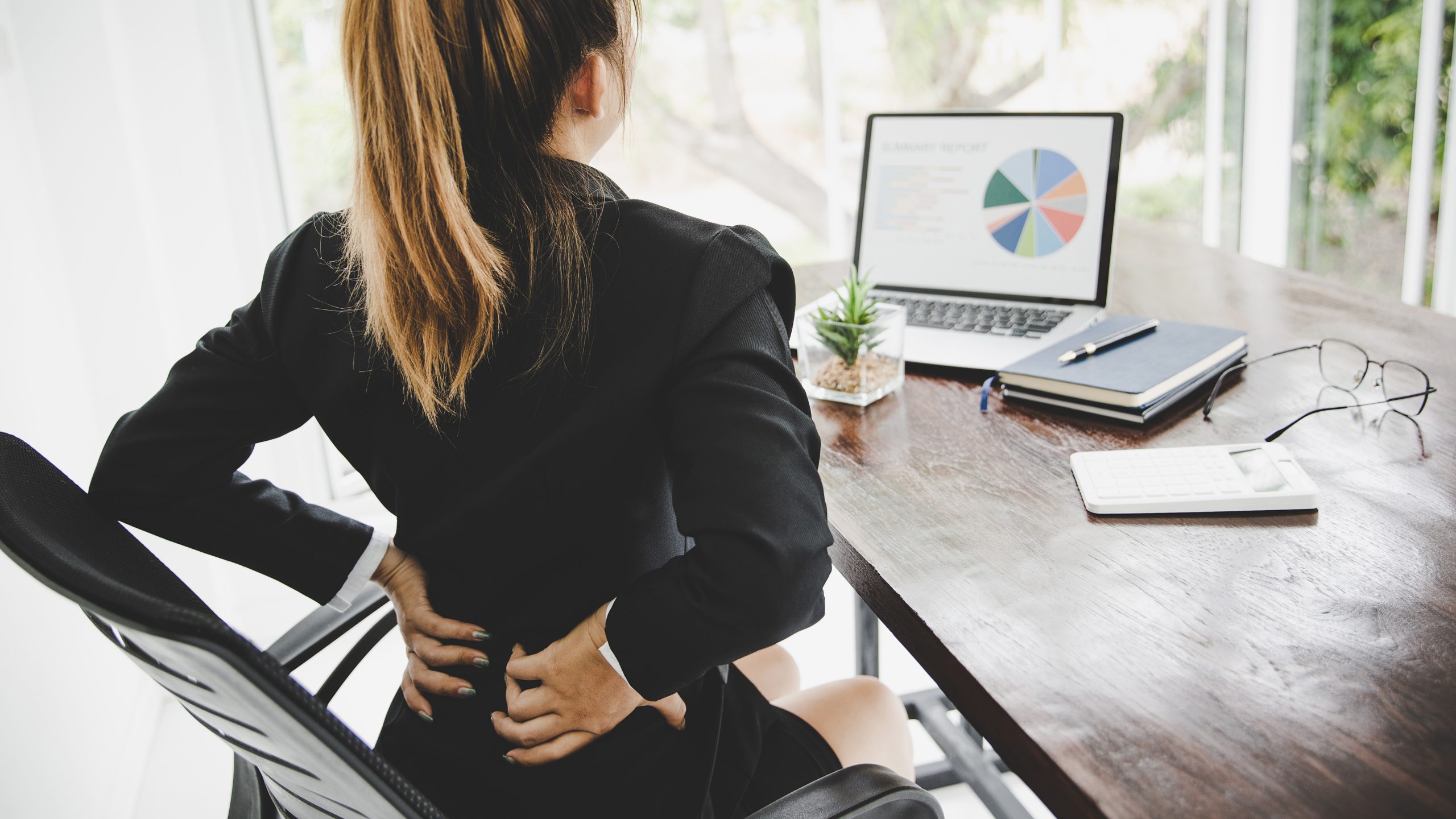 Young business woman at the office with terrible back pain